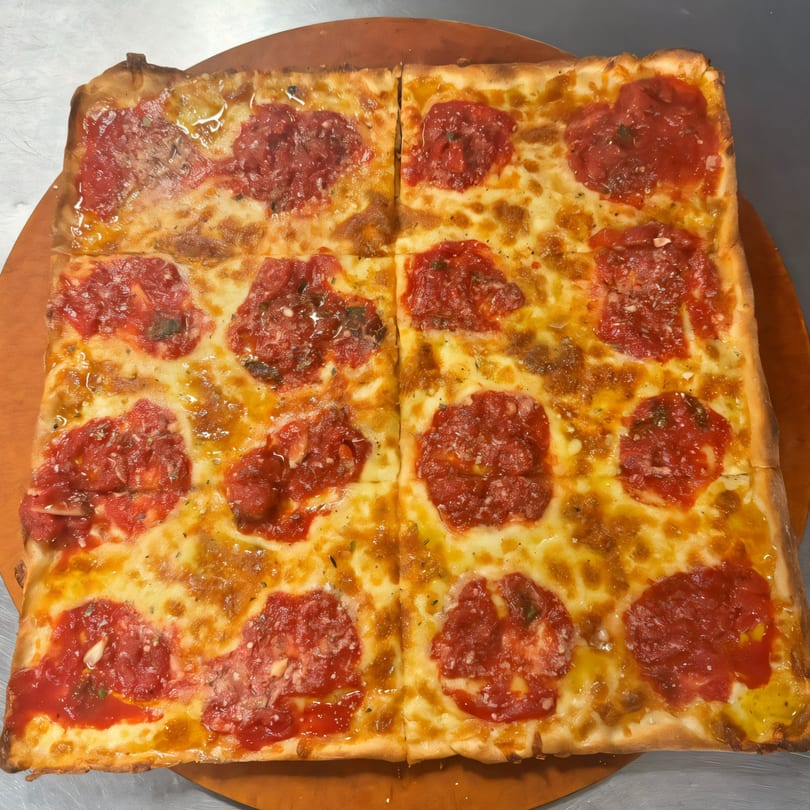 A square Bella Pizza pie, cut into four sections, with melted cheese and dollops of red sauce.