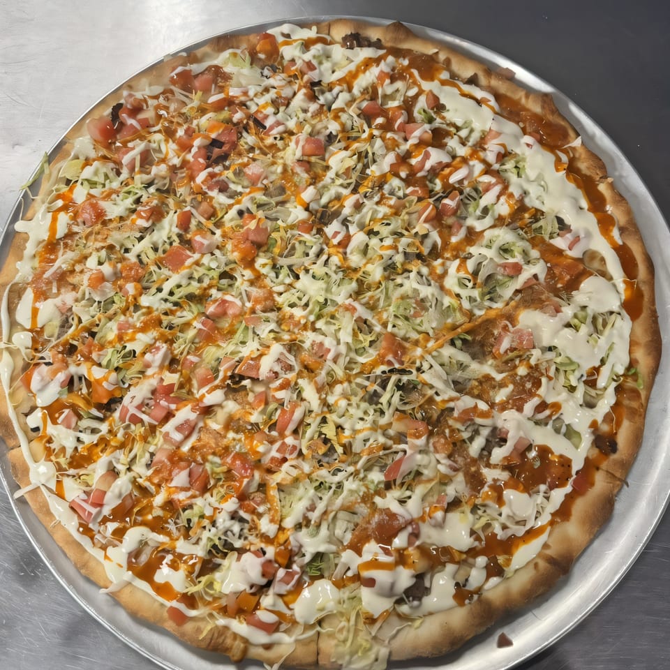 Bella Pizza's taco pizza, topped with shredded lettuce, diced tomatoes, and creamy sauces.