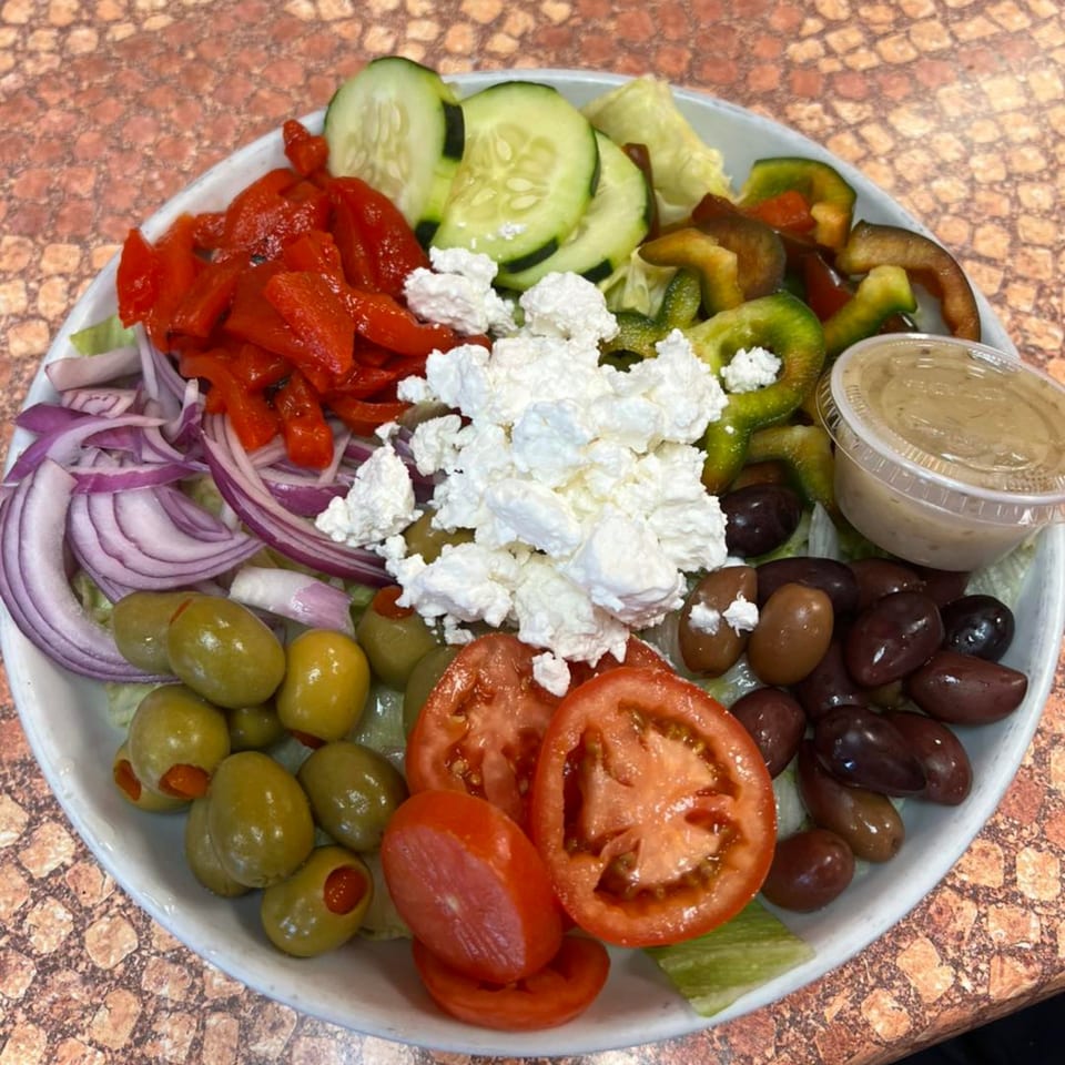 A large Bella Pizza Greek salad with feta, olives, red onions, tomatoes, cucumbers, and peppers.